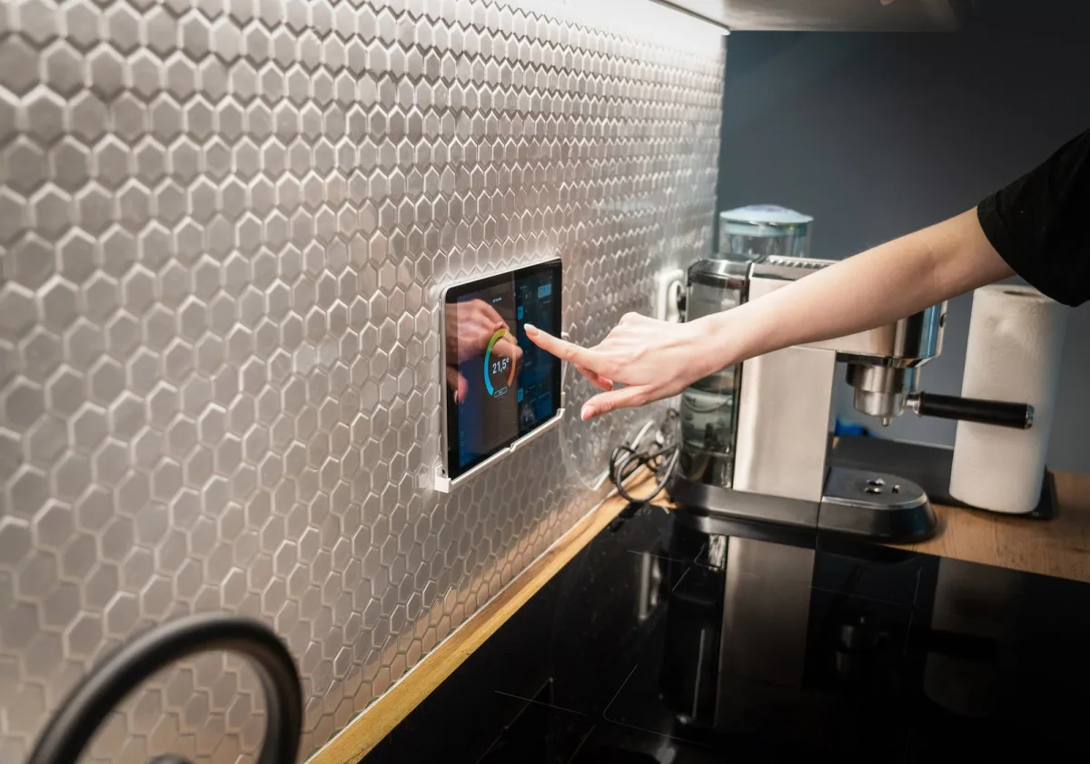 A smart home touchscreen control panel mounted on a wall