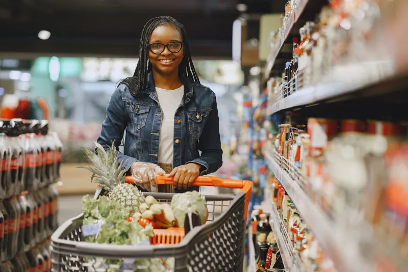 A shopper pushing a cart through a grocery store aisle