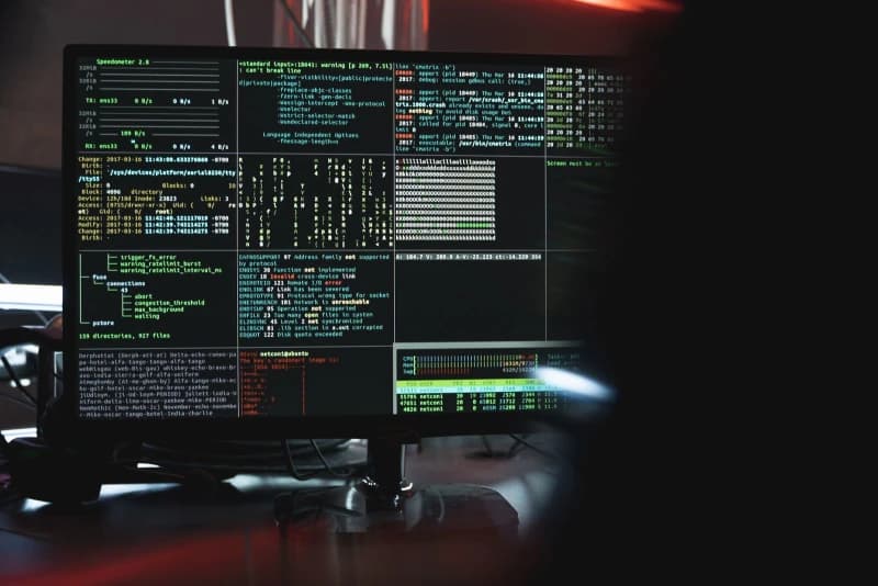 Hooded figure at a computer representing a cyber threat
