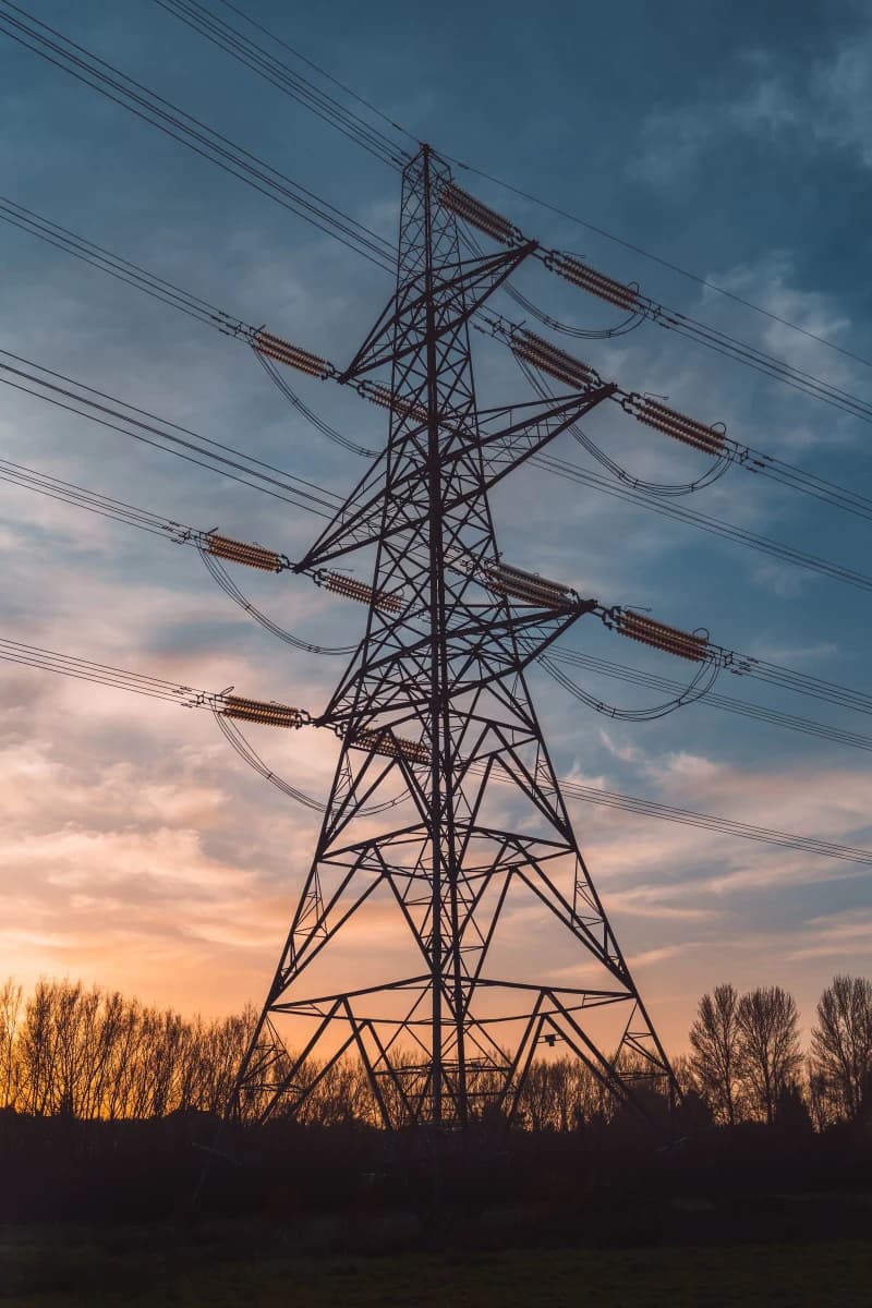 Electricity transmission tower silhouetted against a dusk sky